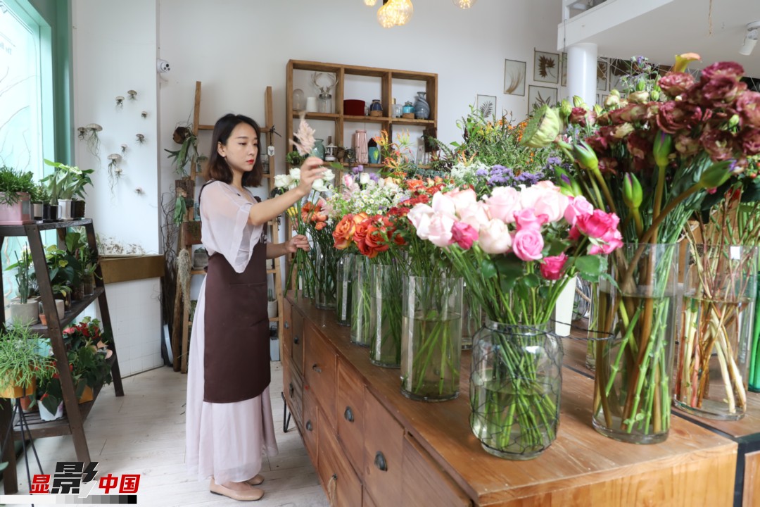 王黎媛是一名河南姑娘，在昆明念完大學(xué)后，就再也舍不下春城的藍(lán)天陽光、青山碧水，更舍不下這里的四時繁花，于是就干脆留了下來，成了一名媒體人。2017年的時候又毅然辭去工作，創(chuàng)業(yè)開起了花店，成了都市里的一名“花房姑娘”。圖為王黎媛在自己的花店中整理鮮花。新華網(wǎng) 周亞平/攝 念新洪/文